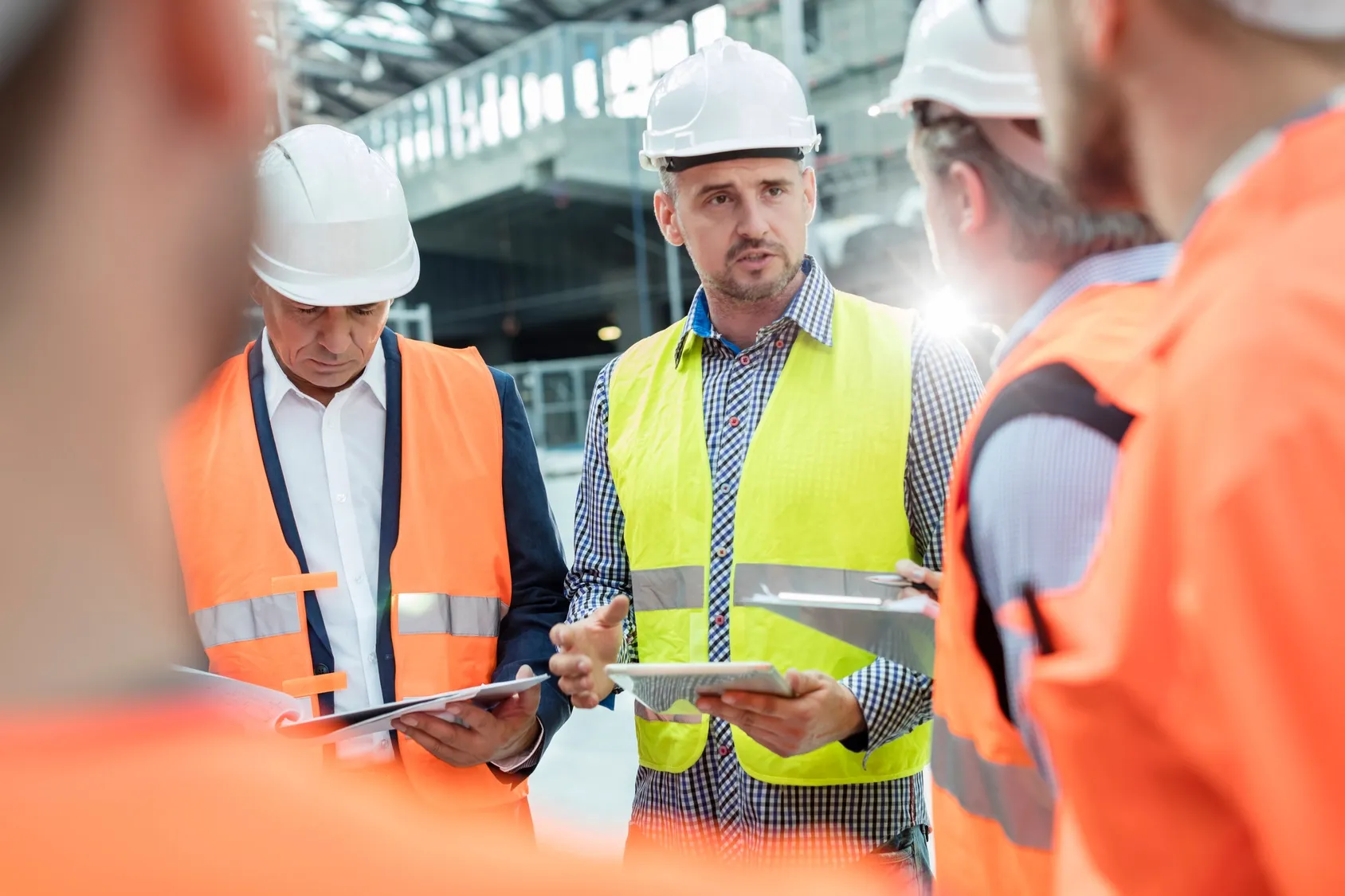 Engineers wearing hard hats discussing blueprints on an active construction site.